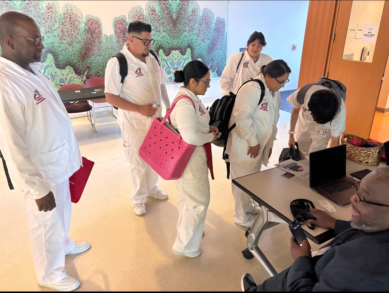 Attendees gather at an information table to explore materials and speak with a representative.